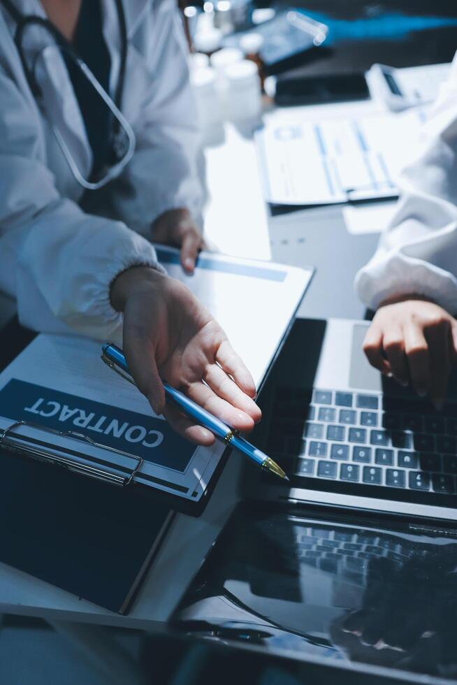 A doctor is using a laptop and a pen photo