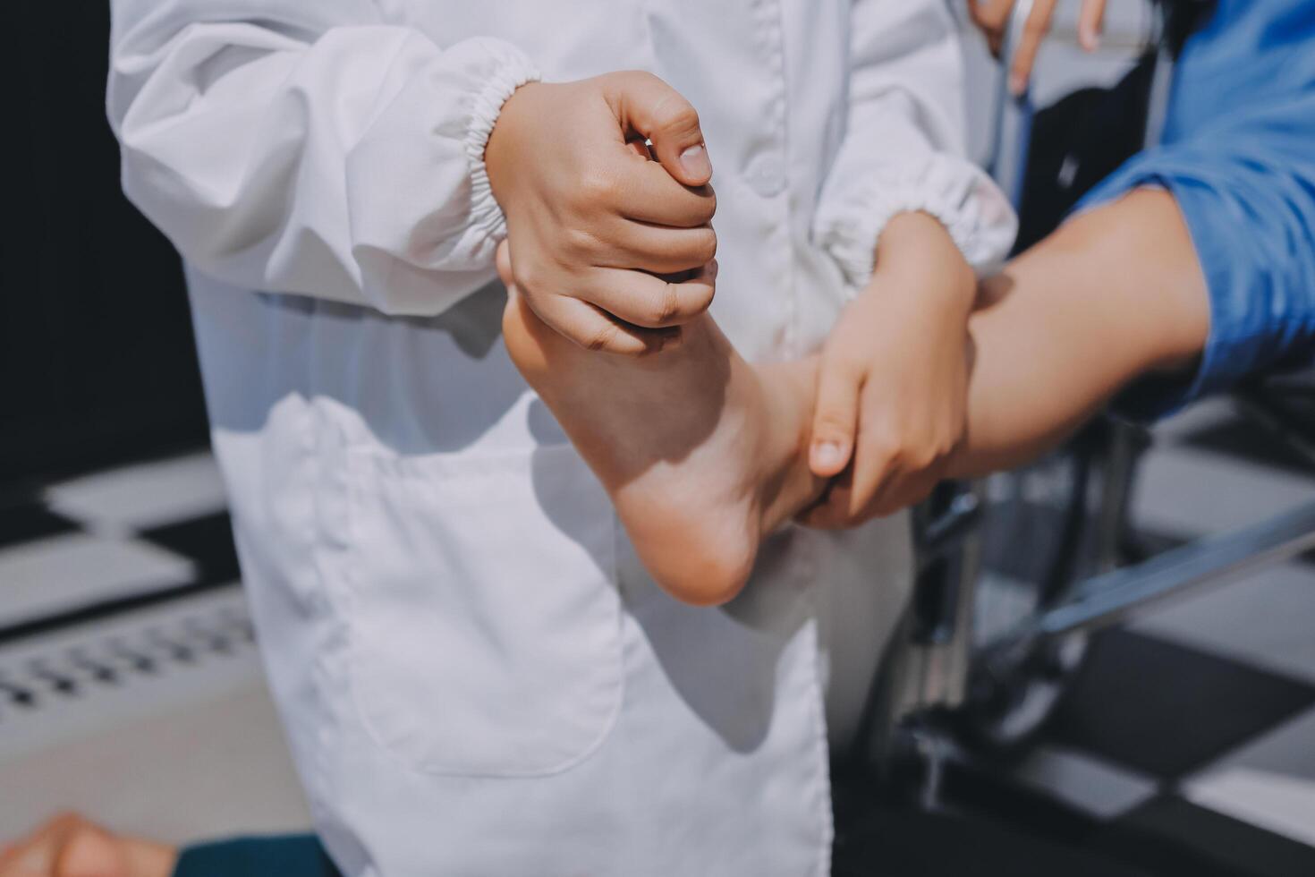 A person in a white coat is holding the foot of a child photo
