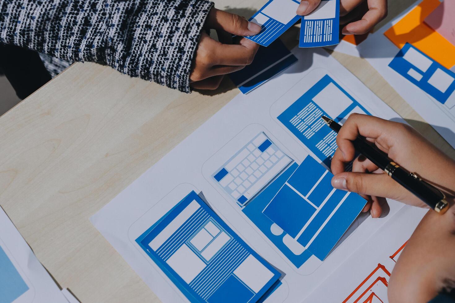 Two people working on a project with paper and blue and white paper photo