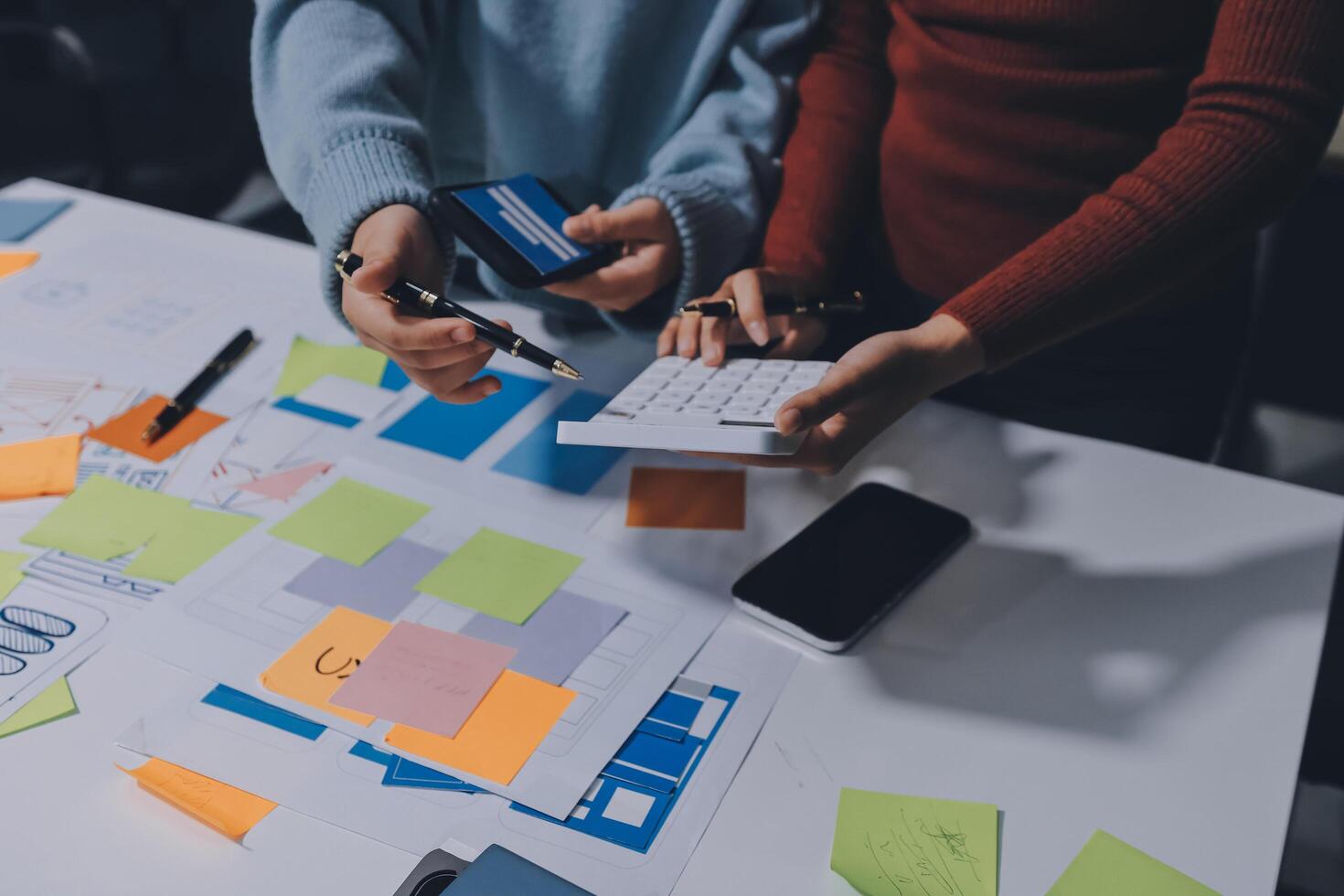 Two people working on a project at a table with paper and sticky notes photo