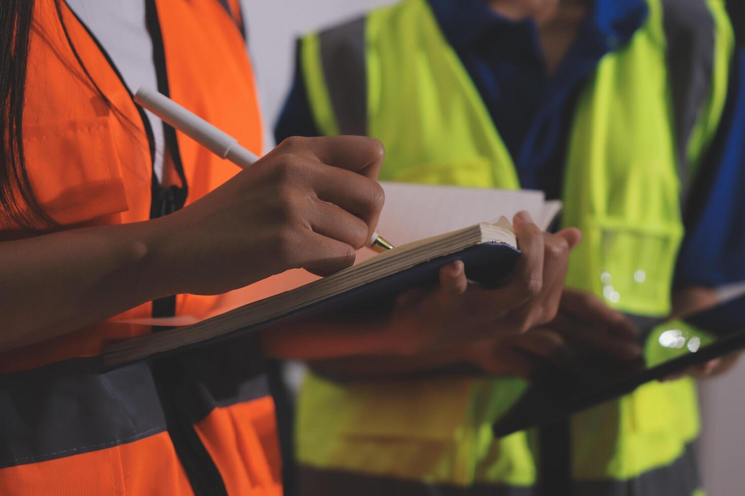 Two people in safety vests holding a notebook photo