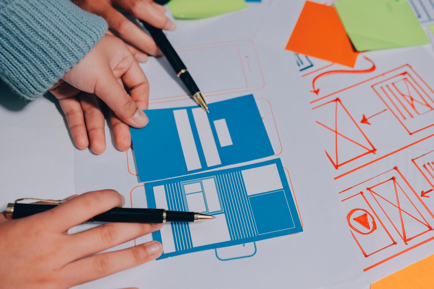 A person is holding a pen and paper with a piece of paper with a design on it photo