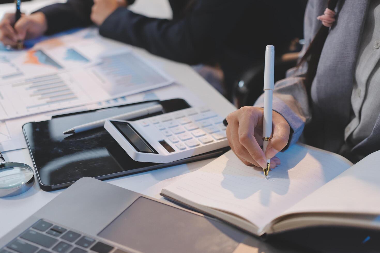 Business people working on a laptop and writing on a notebook photo