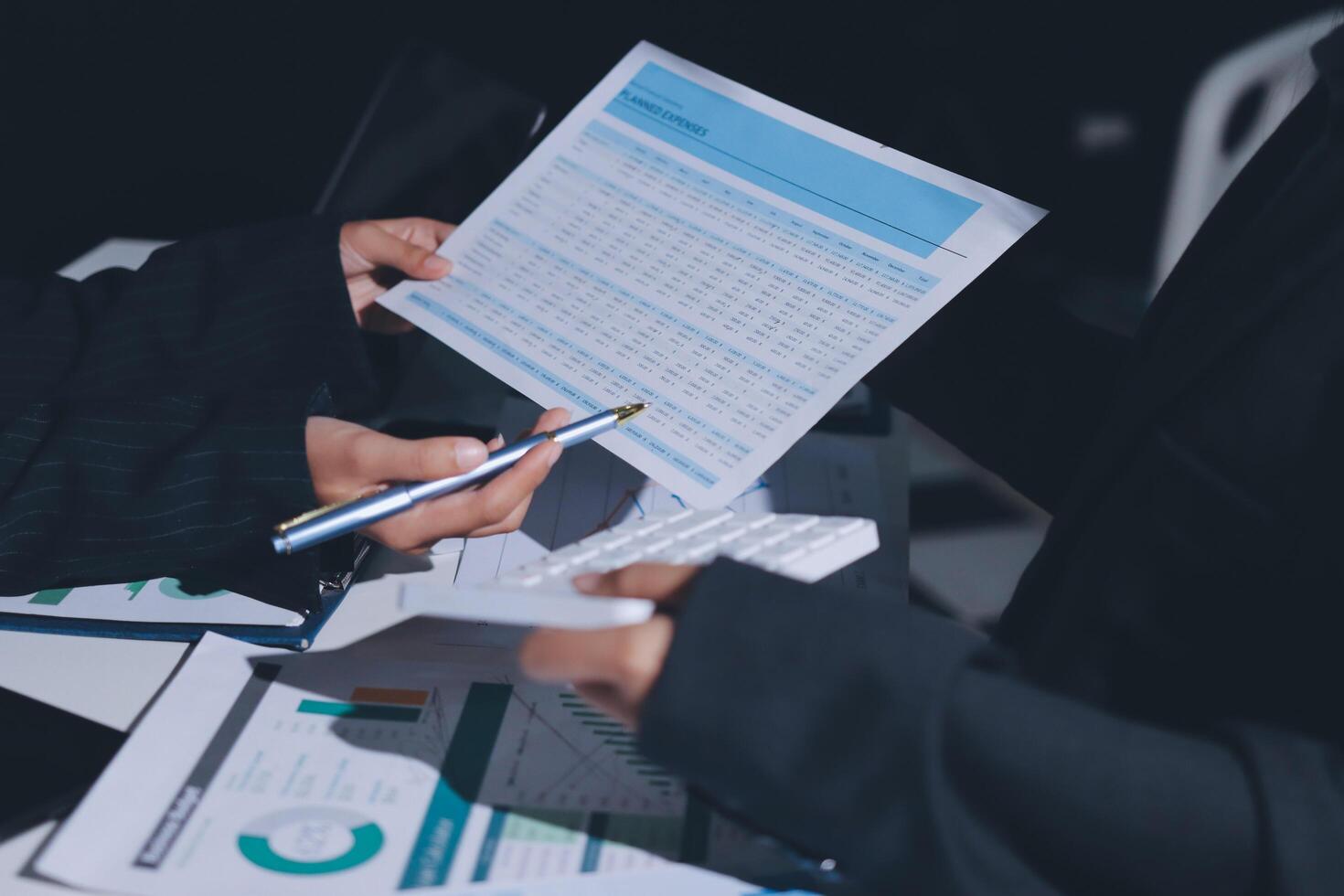 Business people holding papers and pen while looking at a document photo