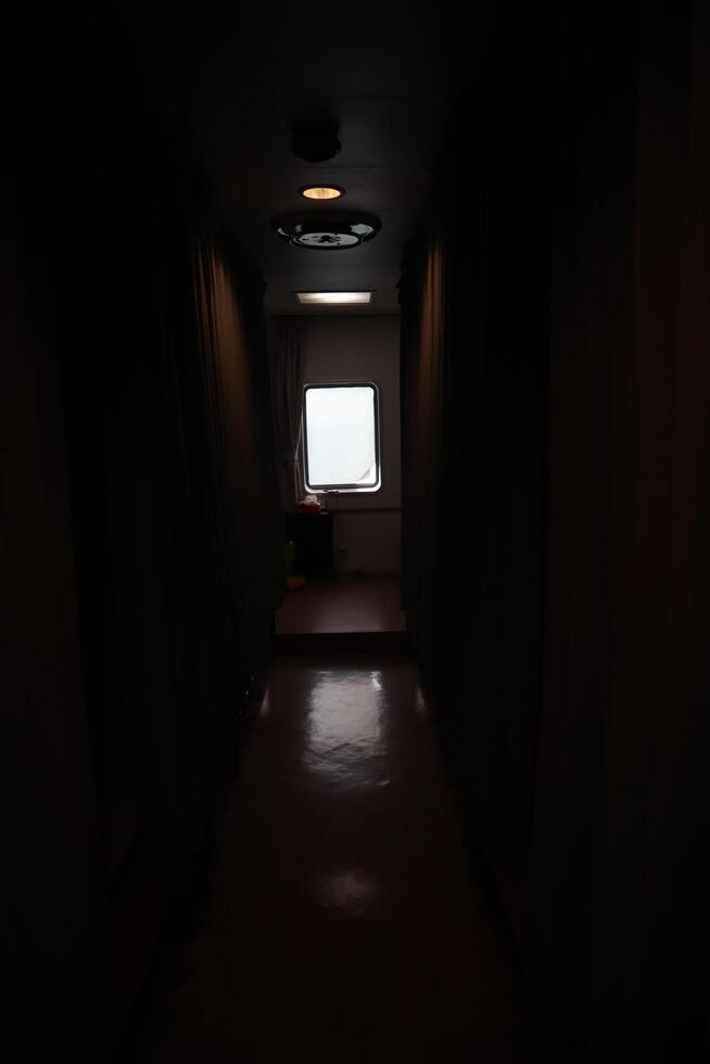 A dark hallway with a light shining through the window photo
