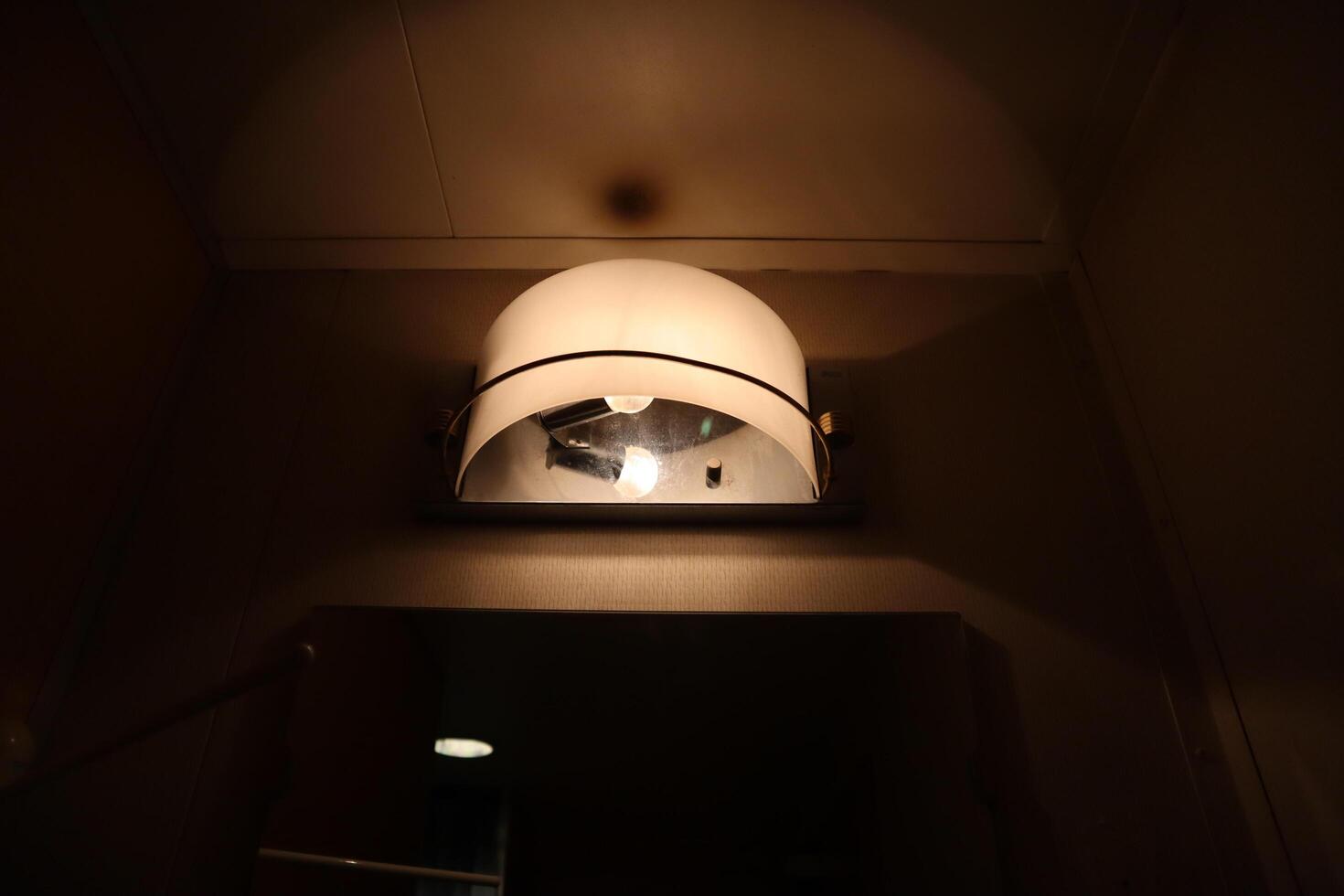 A light is shining on a light fixture in a bathroom photo