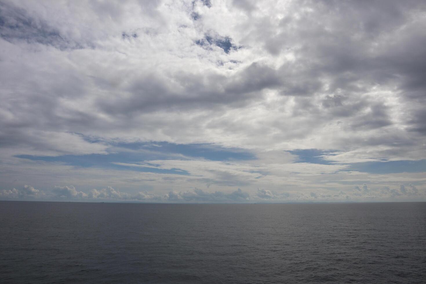 A cloudy sky over the ocean with a boat in the distance photo