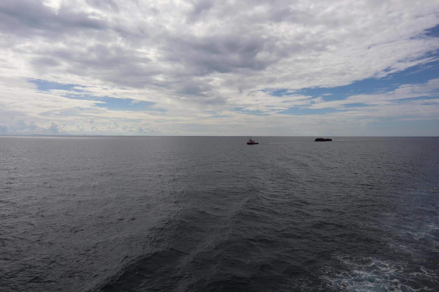 A boat is out in the ocean with a few clouds in the sky photo
