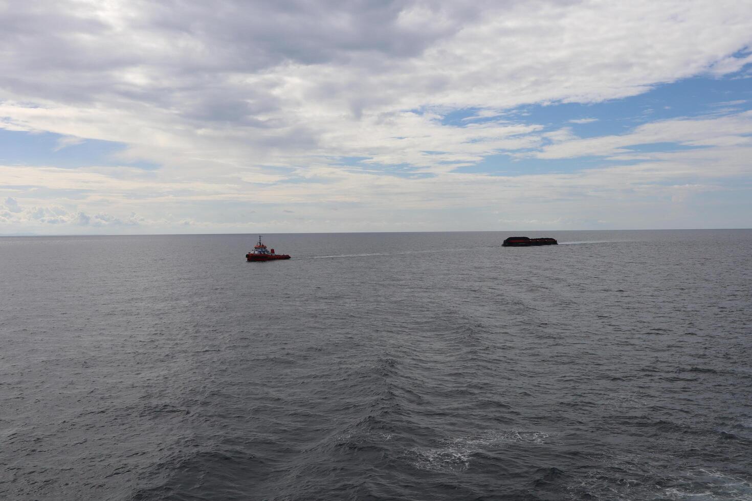 A boat in the ocean with a small boat in the distance photo
