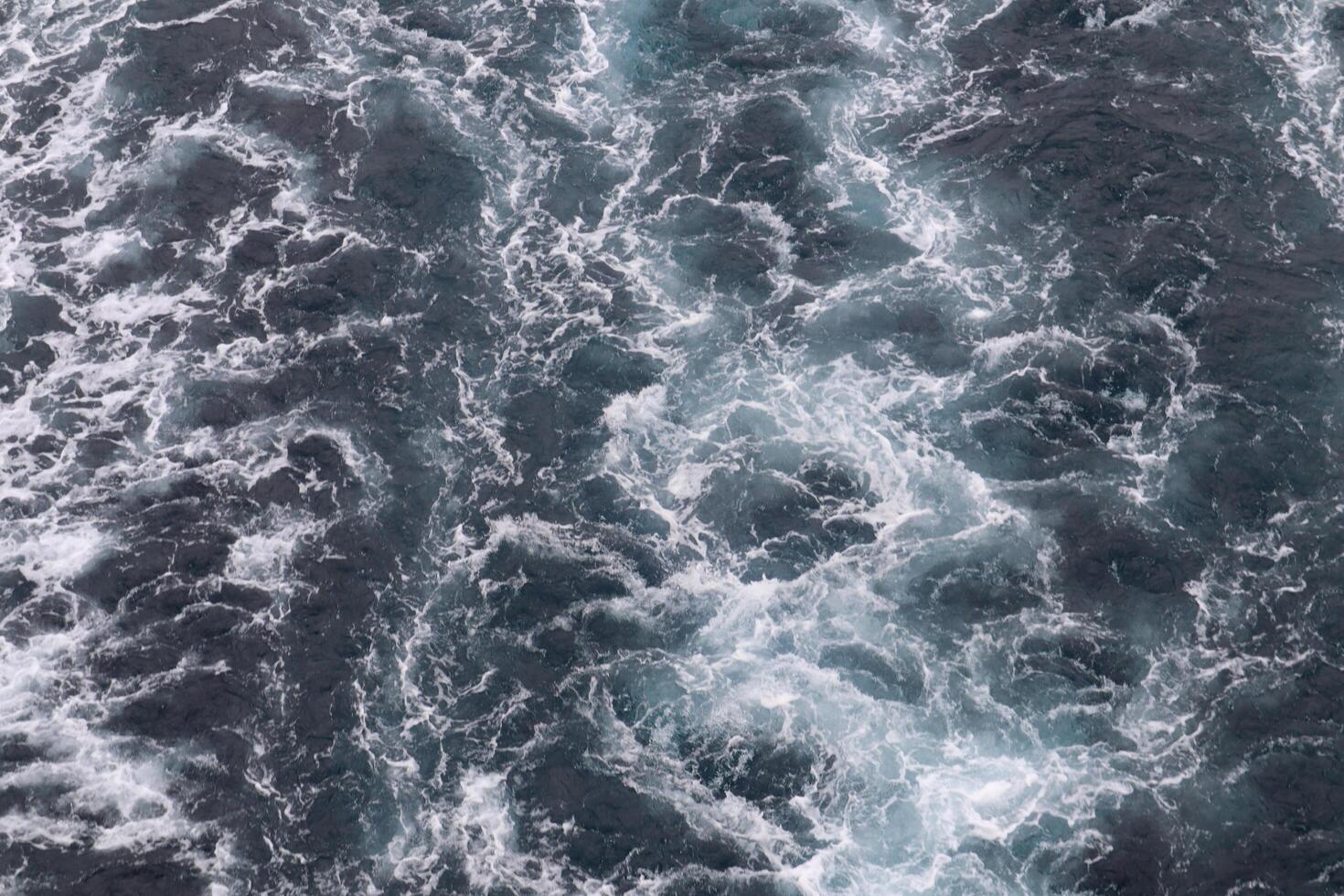 An aerial view of the ocean with white and blue water photo