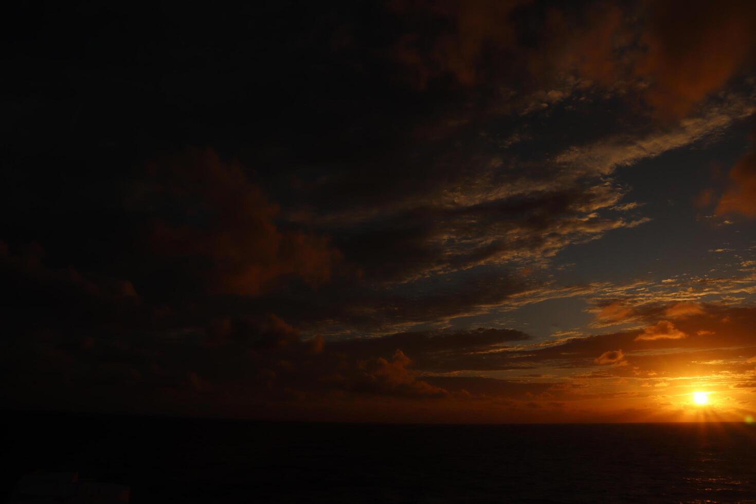 A sunset over the ocean with a plane flying over it photo