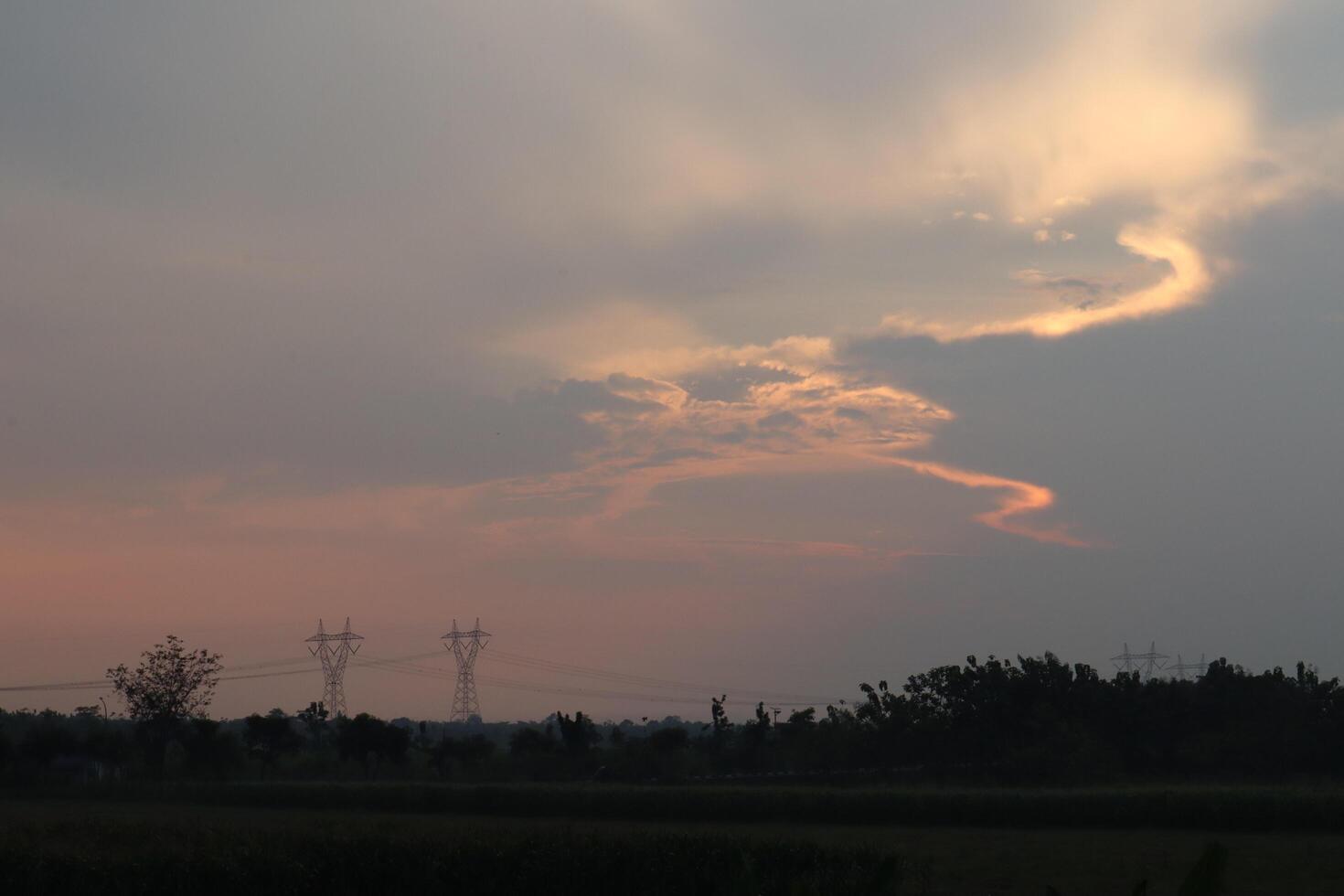 A plane flying over a field with power lines in the background photo