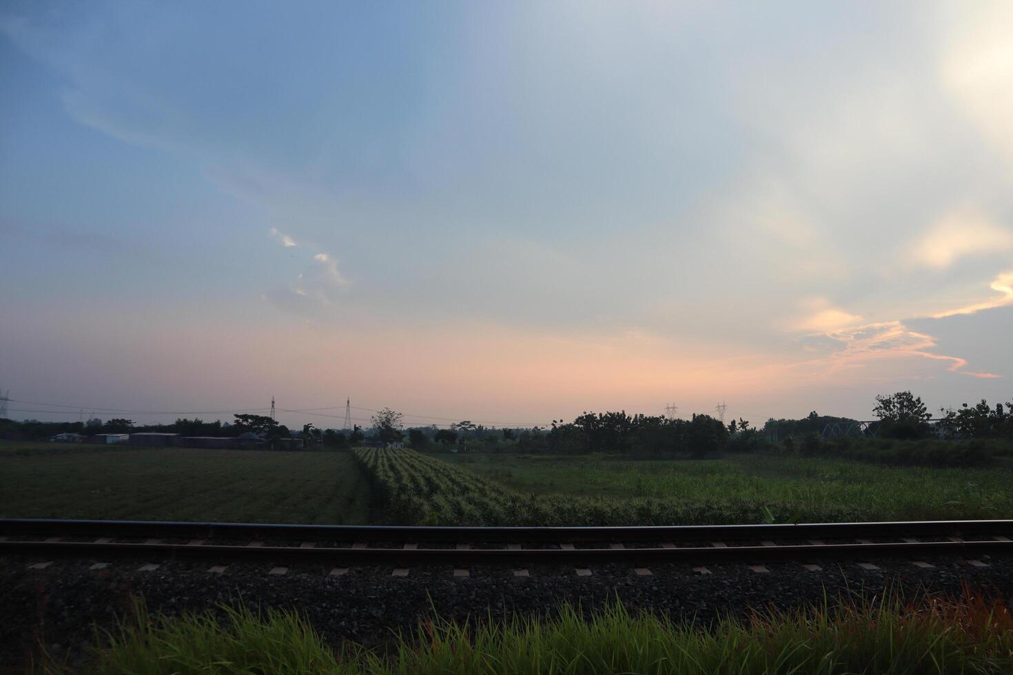 A train is traveling through a field with a sky in the background photo