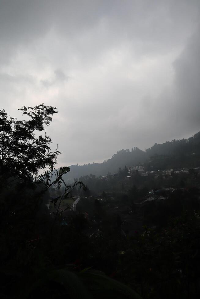 A cloudy sky with a few trees in the foreground photo