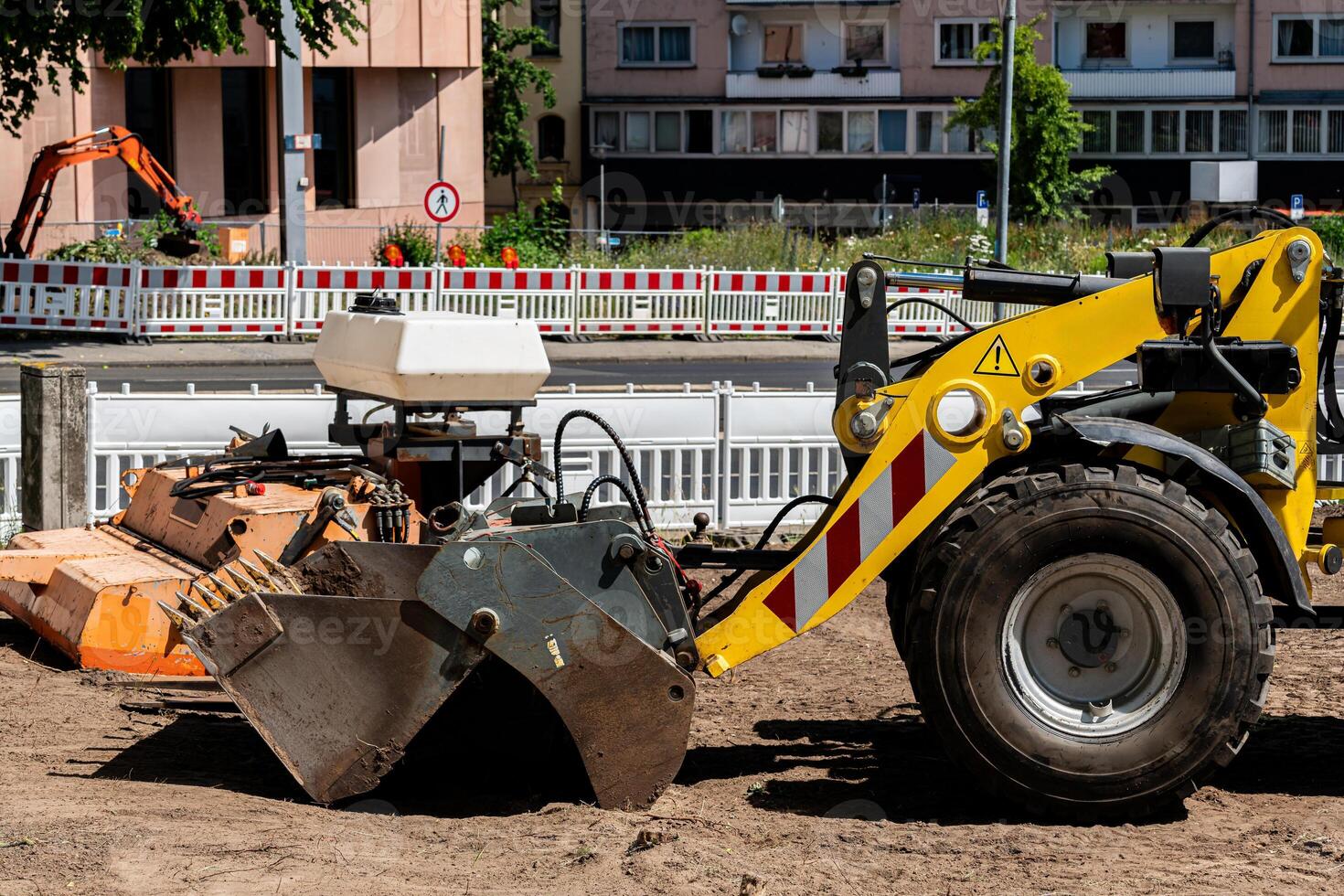 A yellow excavator is seen operating on a construction site in a city photo