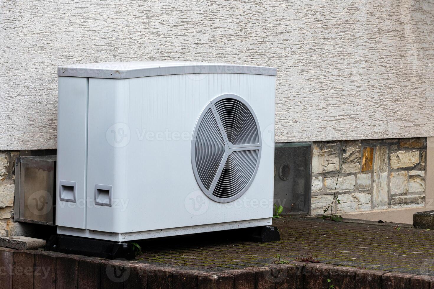 An air conditioning unit is situated outside a building on a hard photo