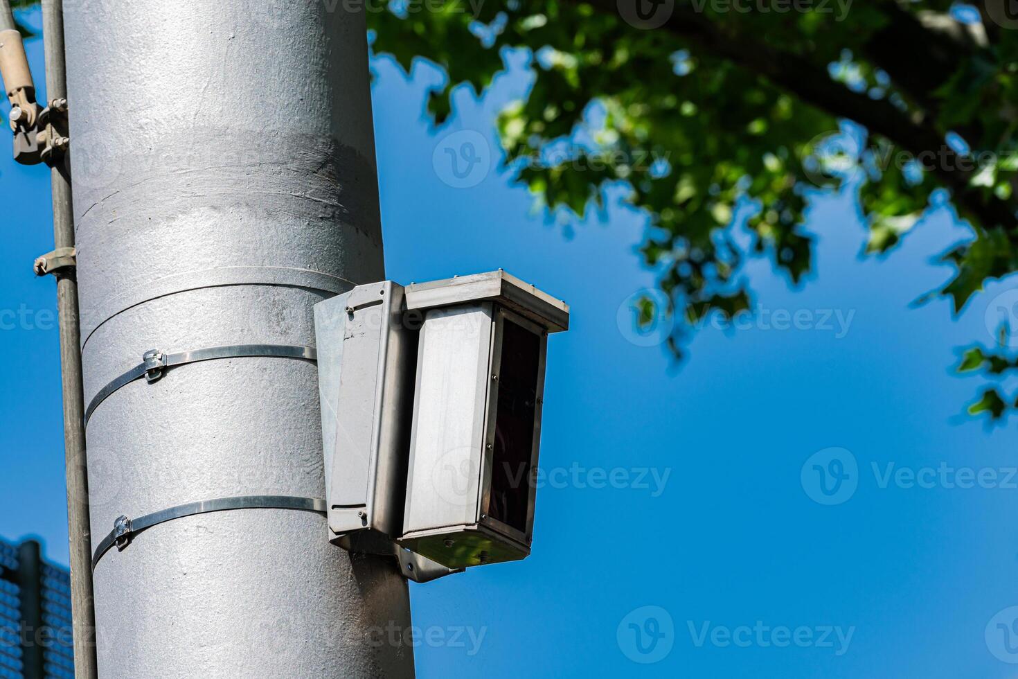 A surveillance camera attached to a tall pole monitors the street photo