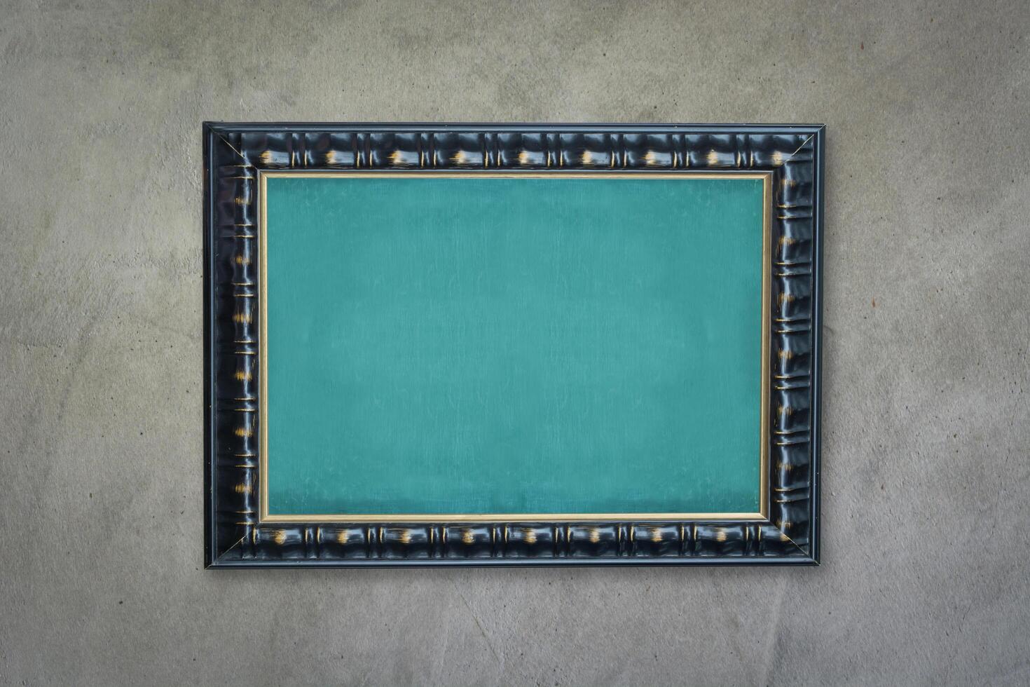 Empty green chalkboard with black wooden frame on grunge cement wall, vintage wall texture background. photo