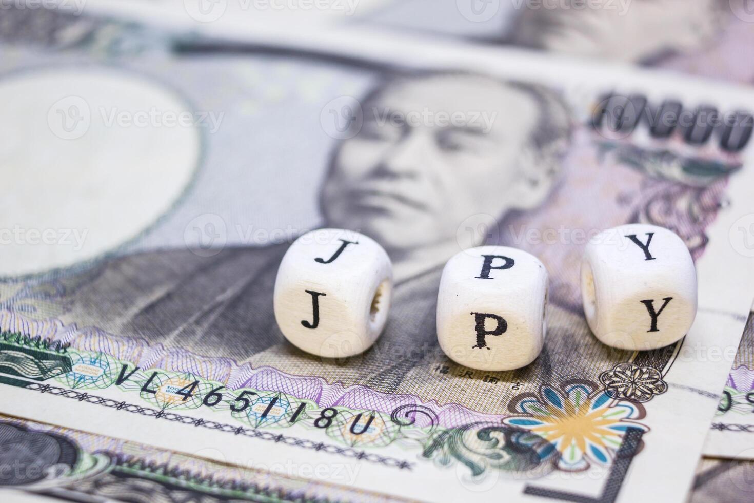 close-up of wooden cube with text J P Y on banknote YEN for business and financial concept. photo