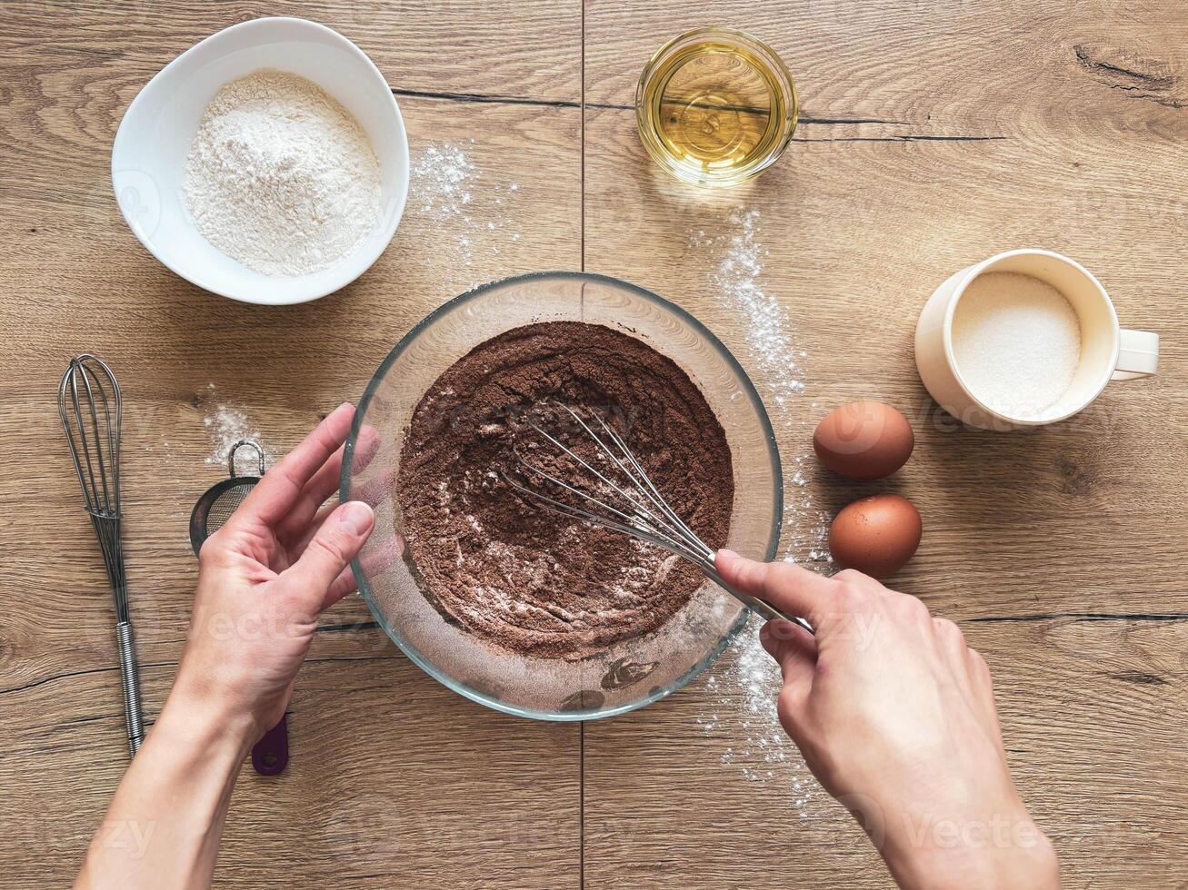 Female hands mixing dry ingredients for chocolate cake with a metal whisk. Homemade baking. photo
