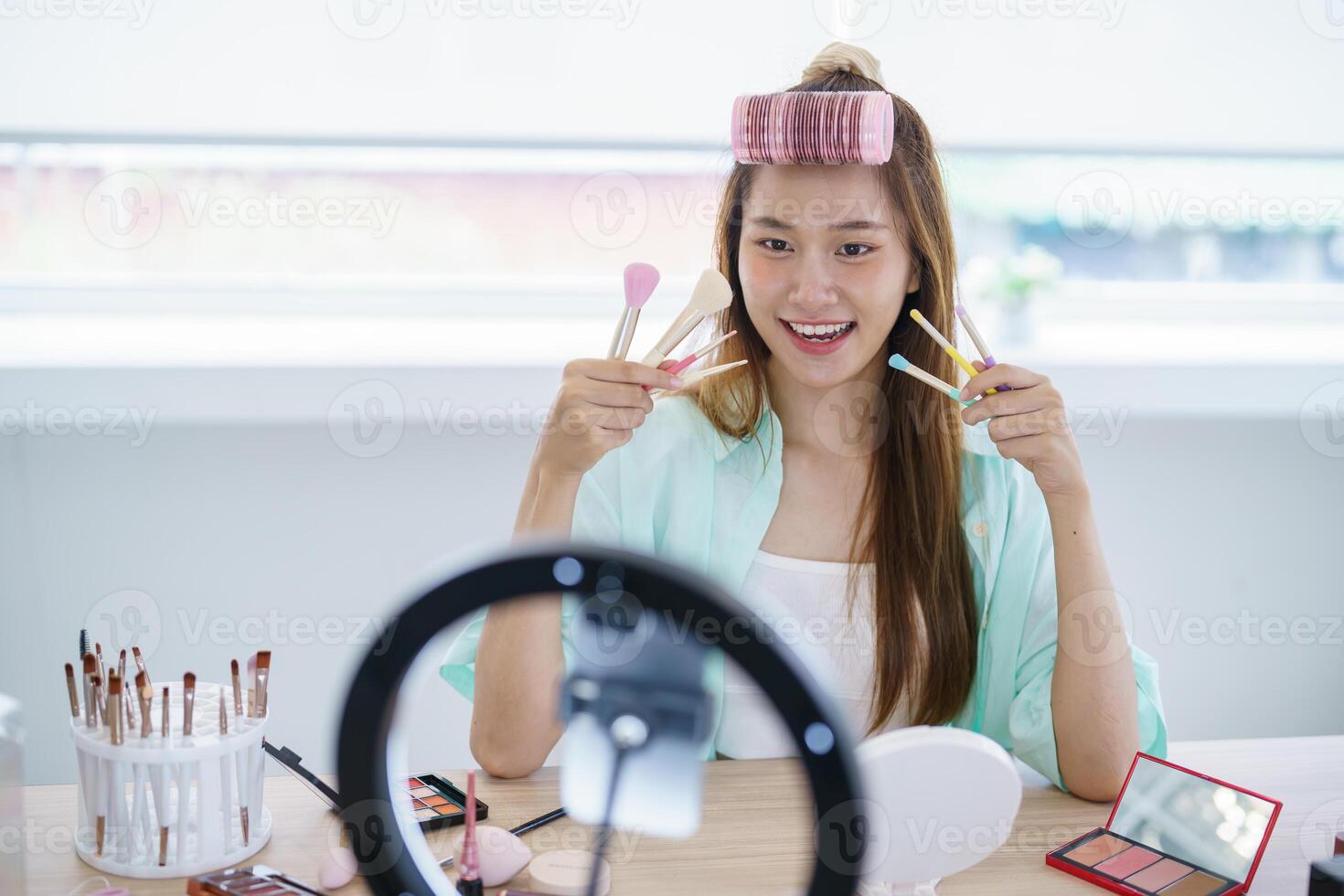a woman makeup artist is holding up two brushes and smiling photo