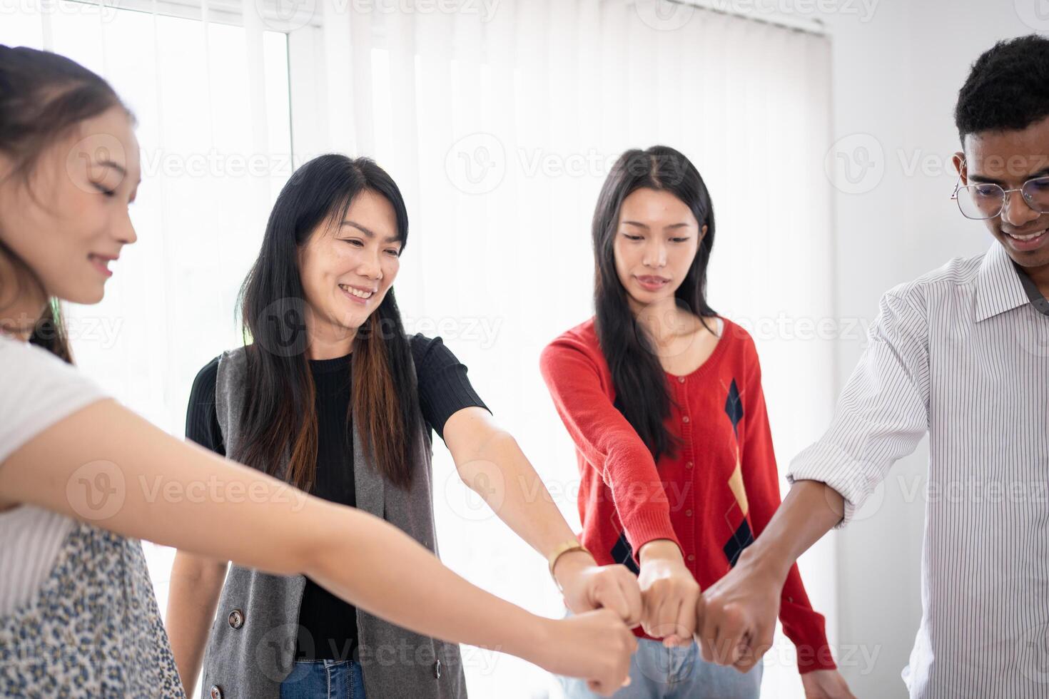 team of business people holding hands in a room photo