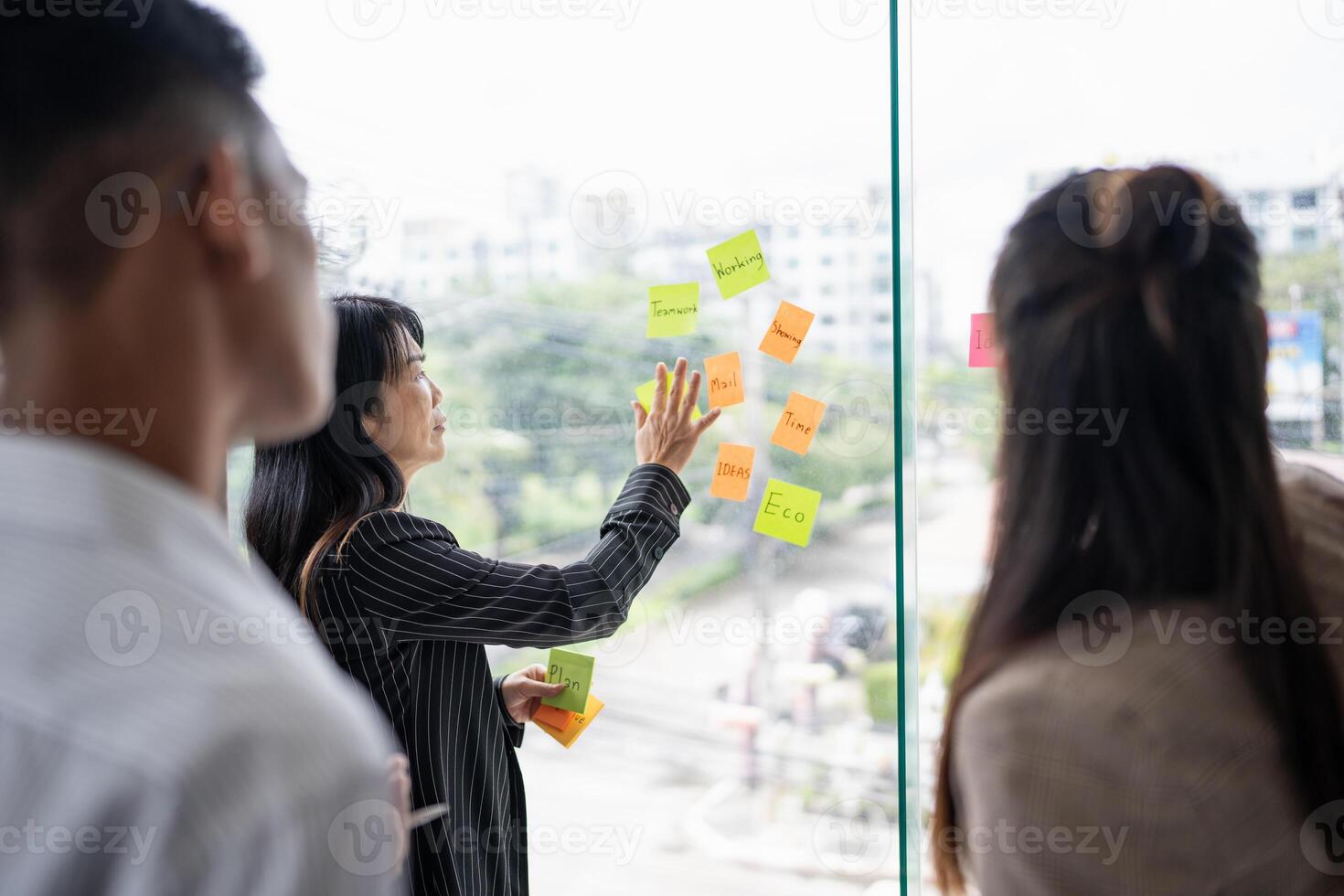 a group of business people standing around a window with sticky notes on them photo