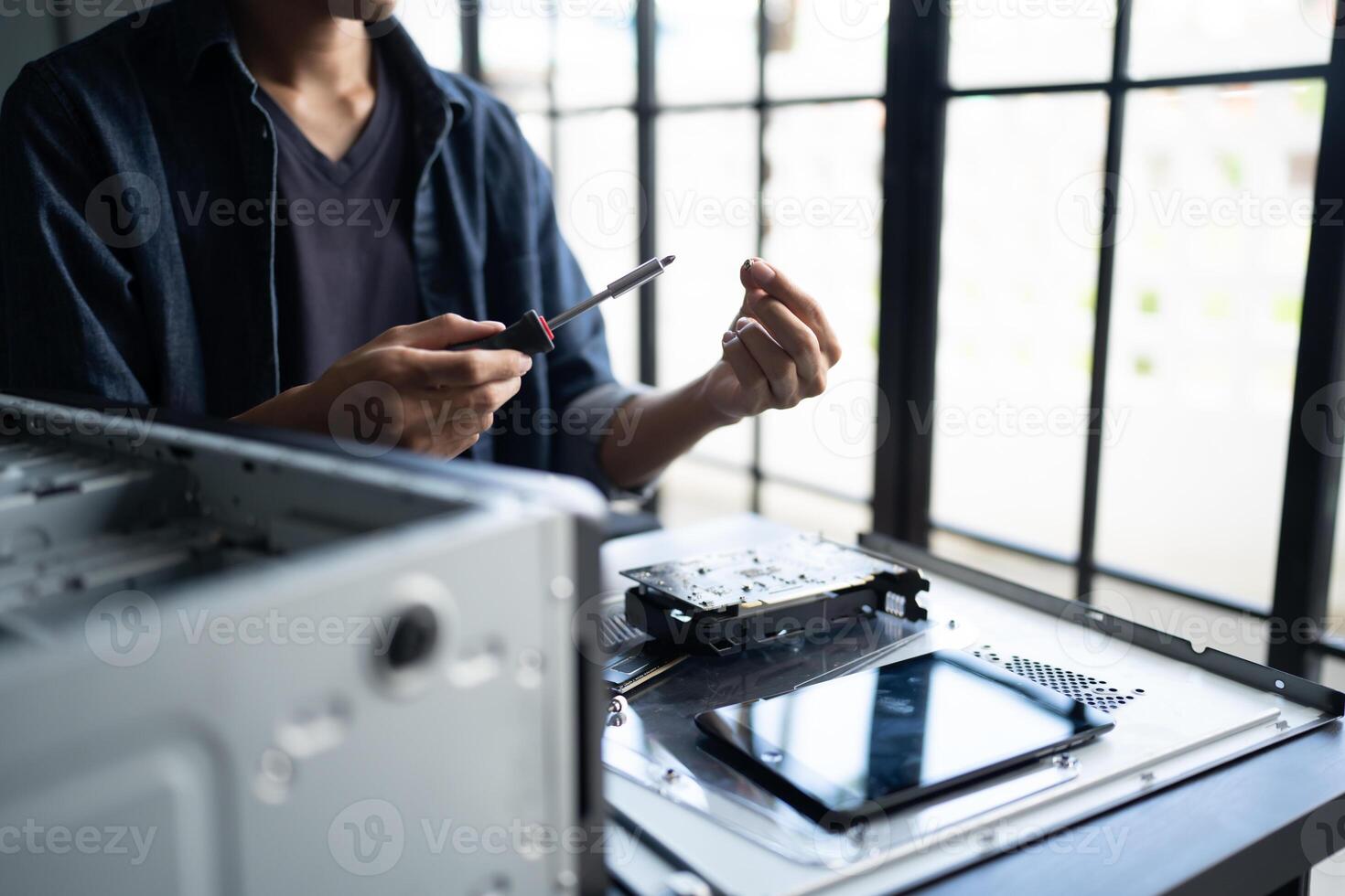 a Engineer installing Hardware is working on a computer with a screwdriver photo