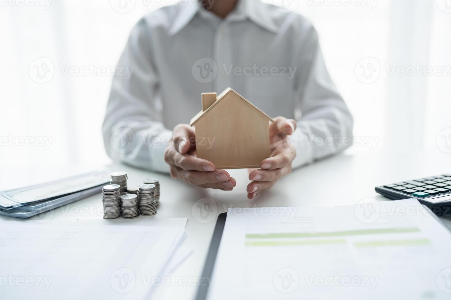 business man holding house model and coins on desk. photo