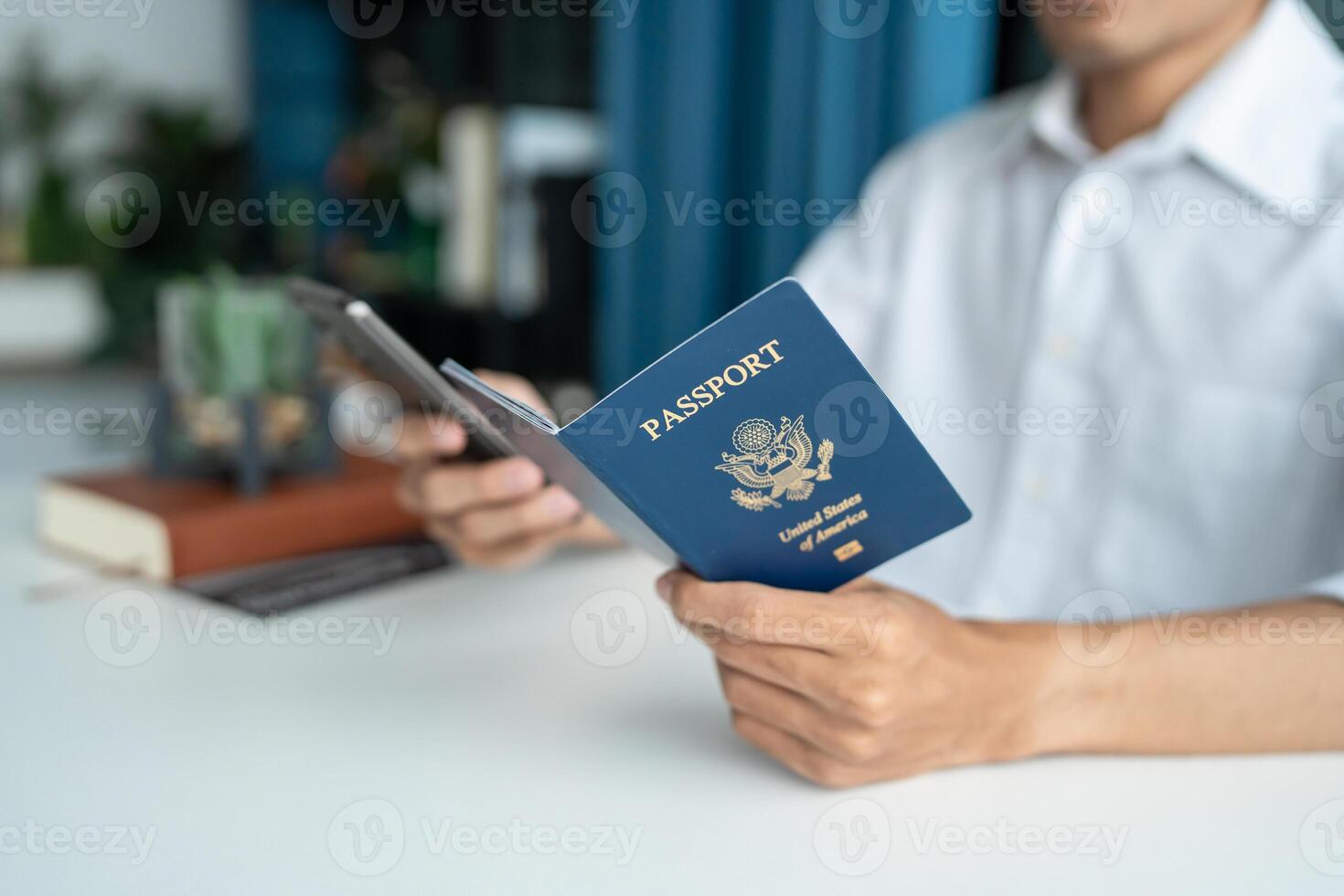 man holding passport and using smartphone at desk photo