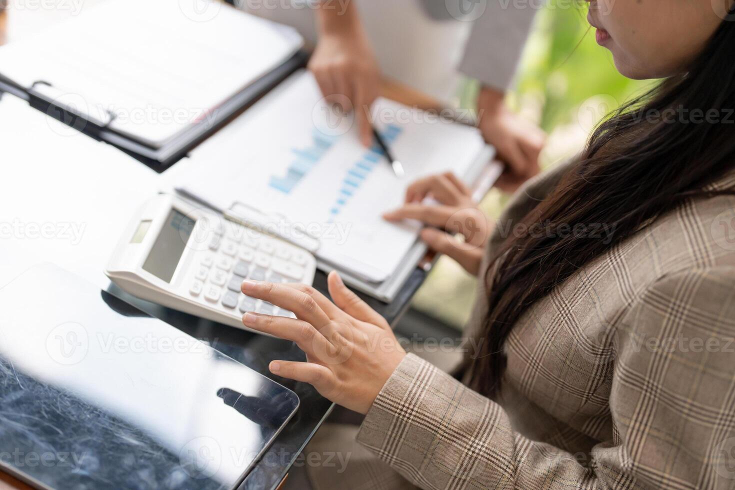a woman in a business suit is using a calculator. photo