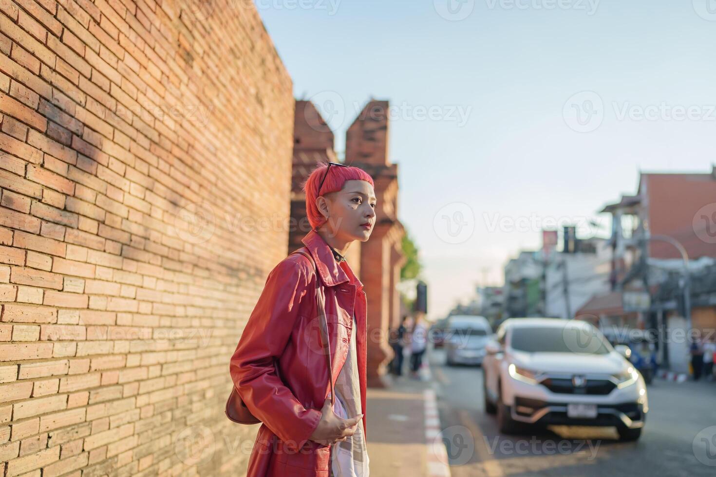Traveler girl woman in red jacket standing on the side of the road photo