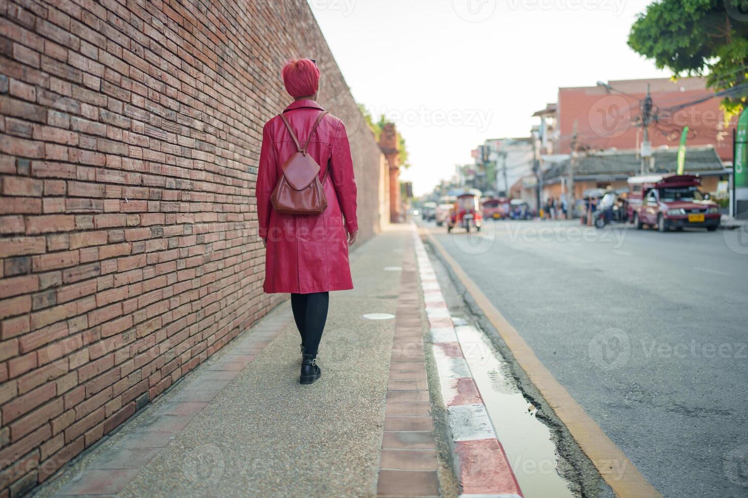 Gen z girl leather fashion with punk woman tourist of local city Southeast Asia travel trendy pink hairstyle young female punk traveler walking around in town. photo