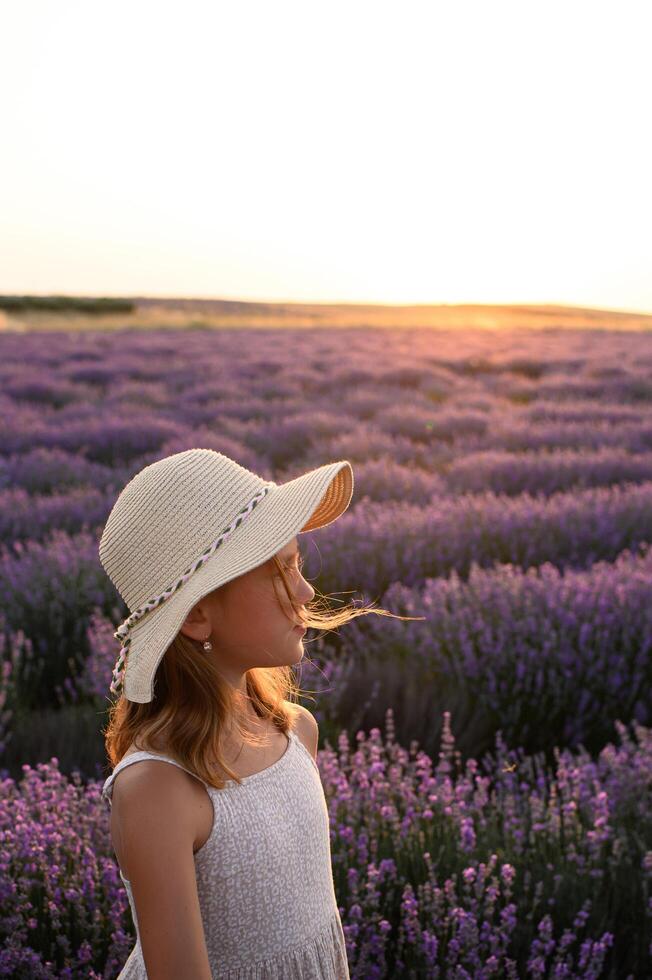 Kid in straw hat enjoying nature in lavender field during twilight. photo