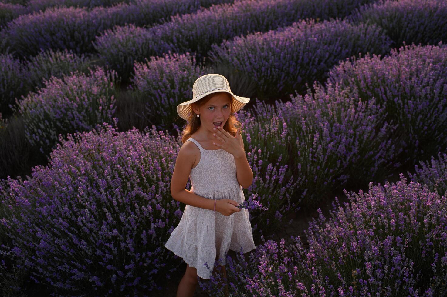 Girl with long hair standing in dreamy lavender meadow during sunset. photo