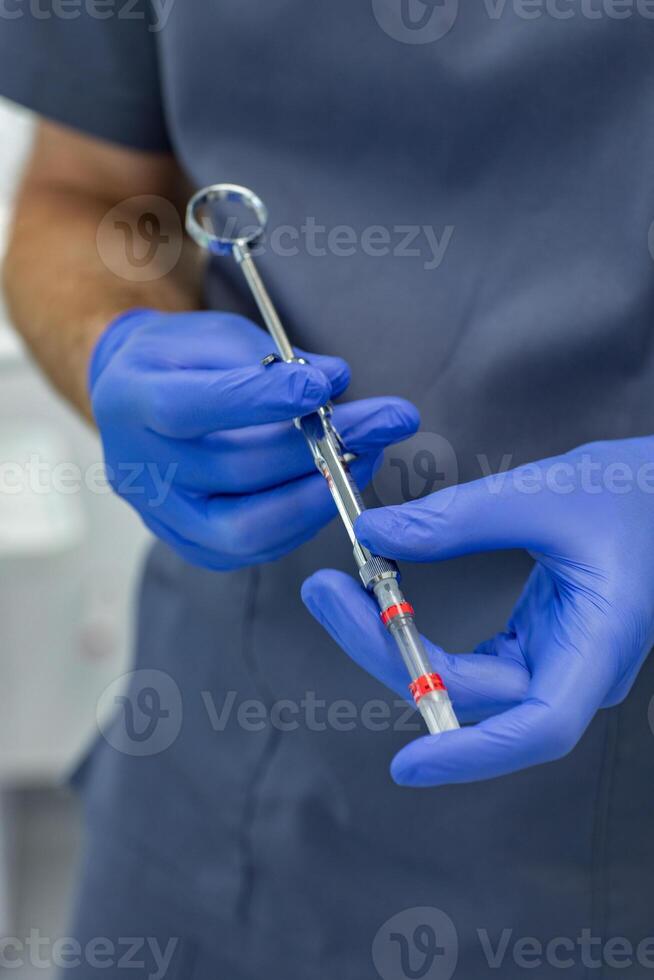 Close-up of dentist hands holding a syringe with a solution photo