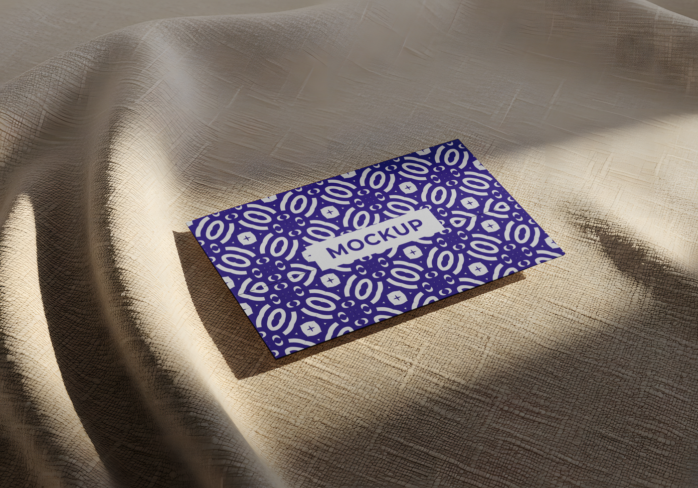 A purple business card with a patterned design rests on a beige fabric psd