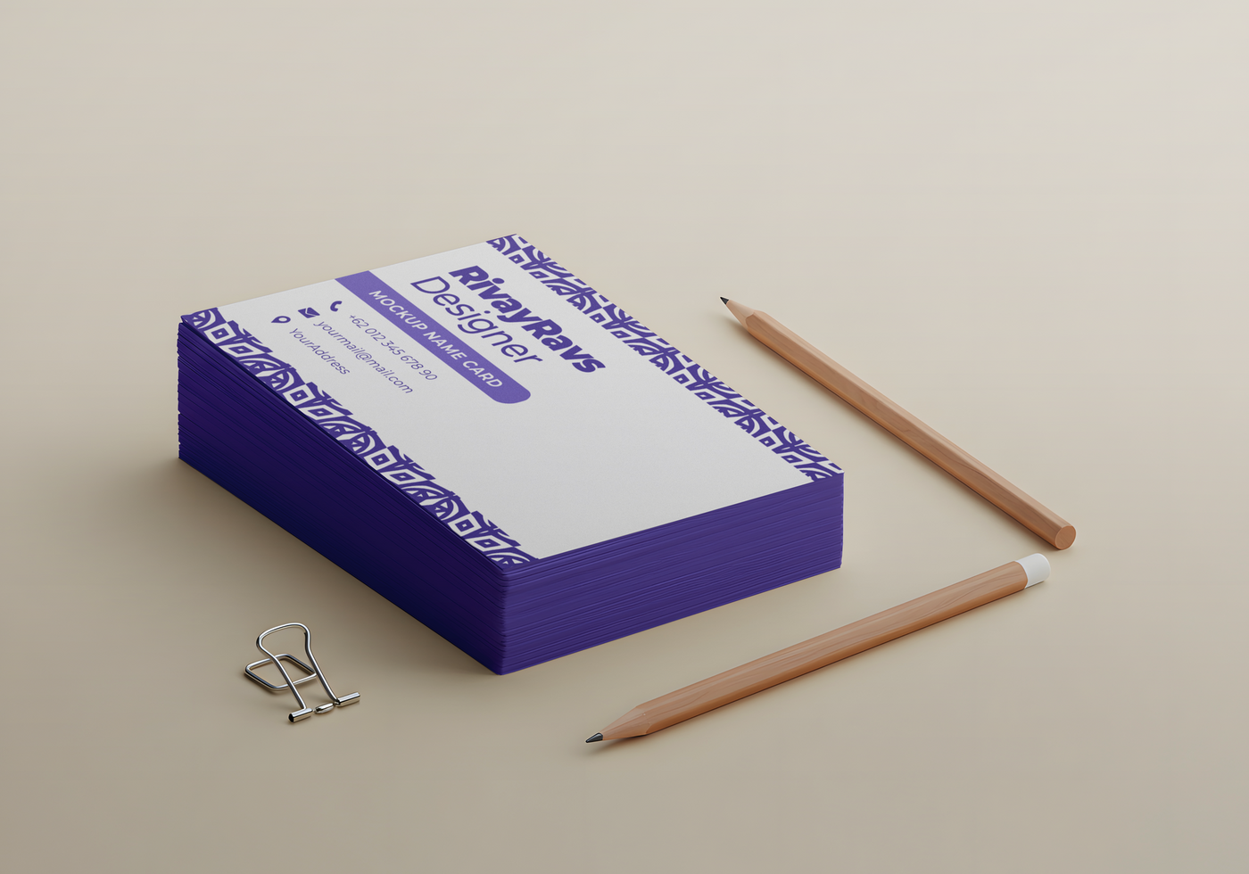 A stack of business cards for RivayRaws Designer sits beside two pencils and a paperclip psd