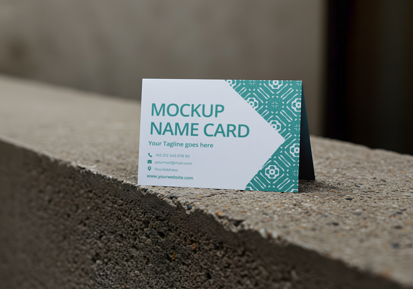 A mockup name card stands on a concrete surface psd