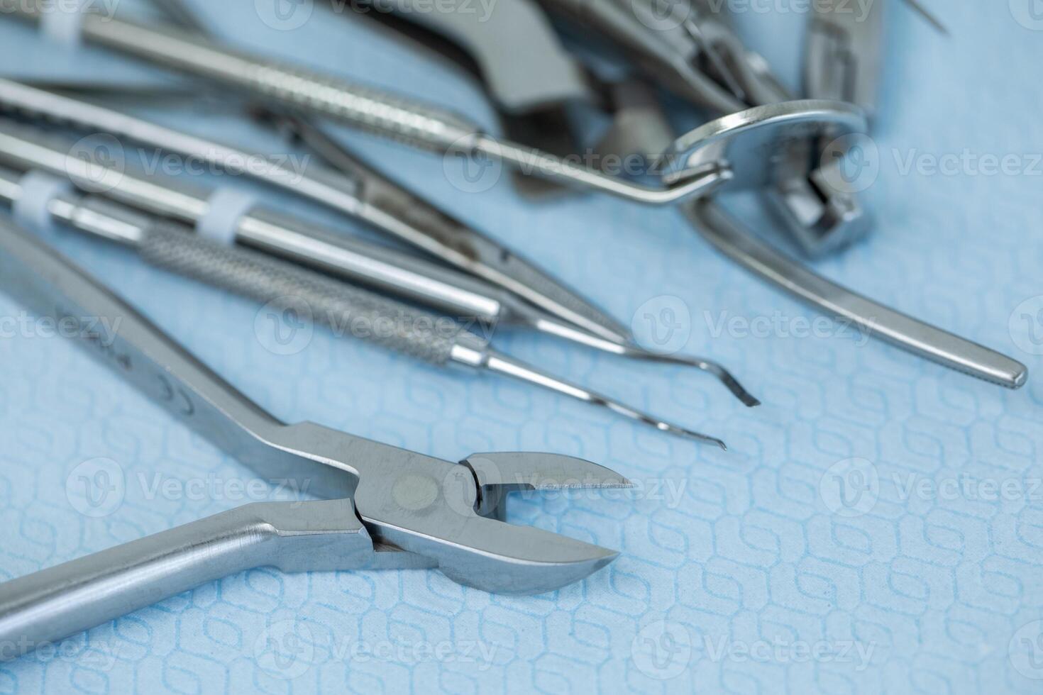 Close-up of various stainless steel dental instruments on a blue surface. photo