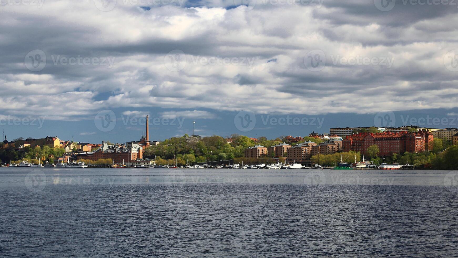 Stockholm waterfront skyline under dramatic clouds viewed across calm water in spring photo