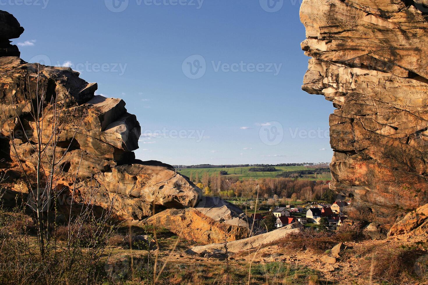 Rocky gap framing a rural village nestled in green fields beyond the Teufelsmauer outcrop in the Harz mountains, Germany photo