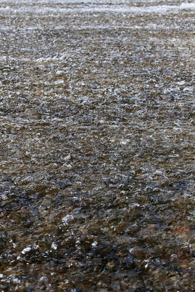 Flowing shallow water with ripples and rocks underneath photo