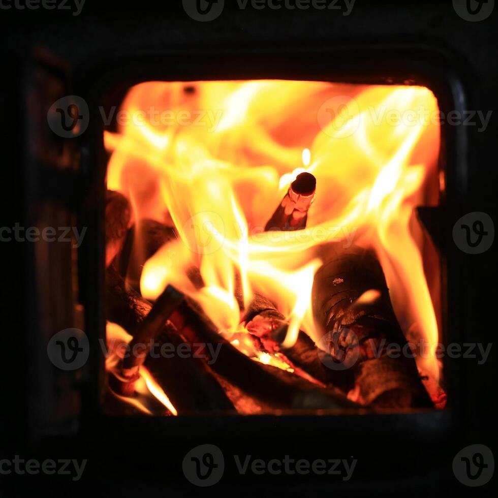 Bright flames engulf kindling in close-up view of active fire inside enclosed cast-iron stove photo