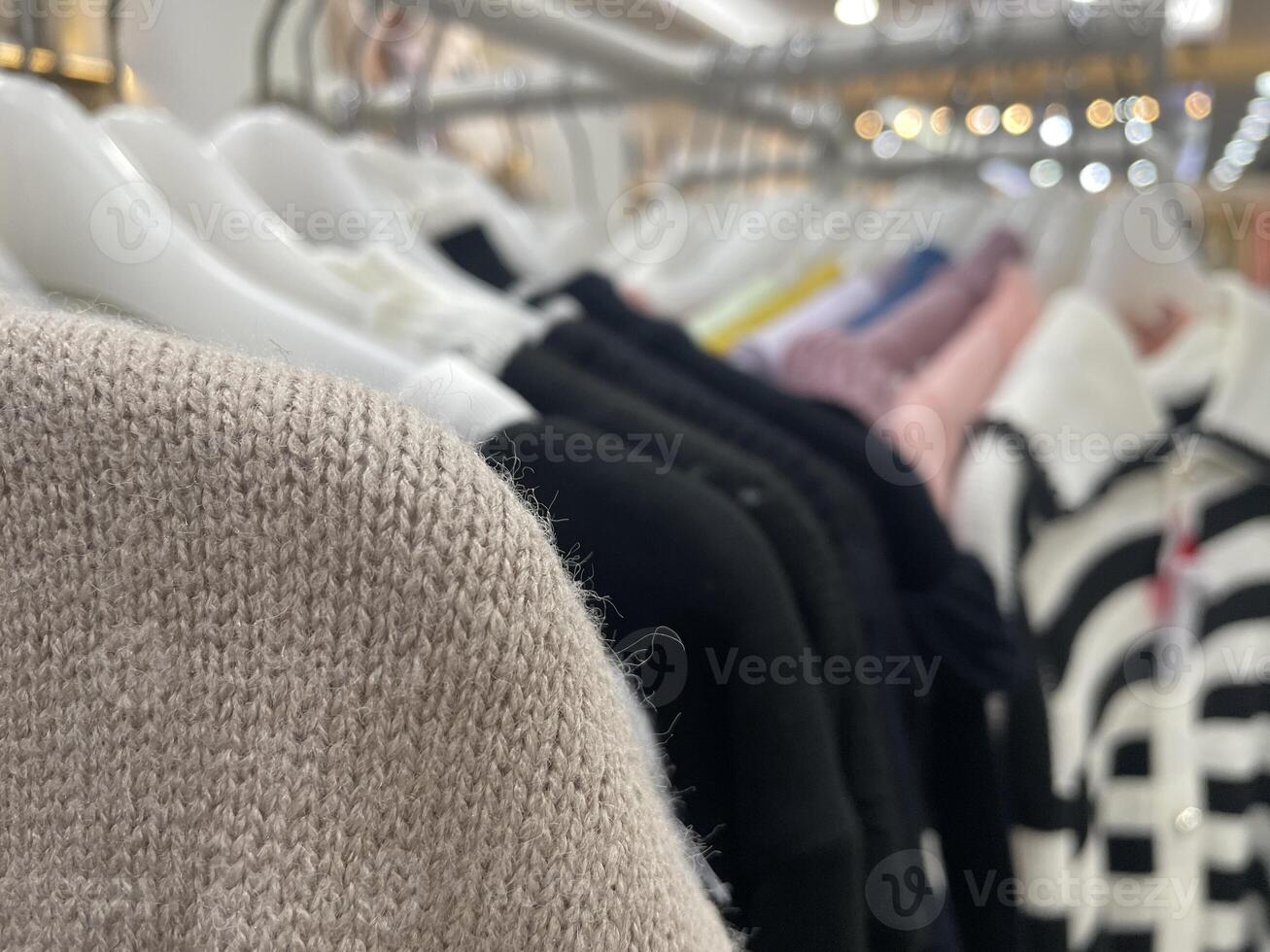Close-Up of Knitted Fabric Texture with Elegant Clothes on Hangers in Fashion Boutique photo