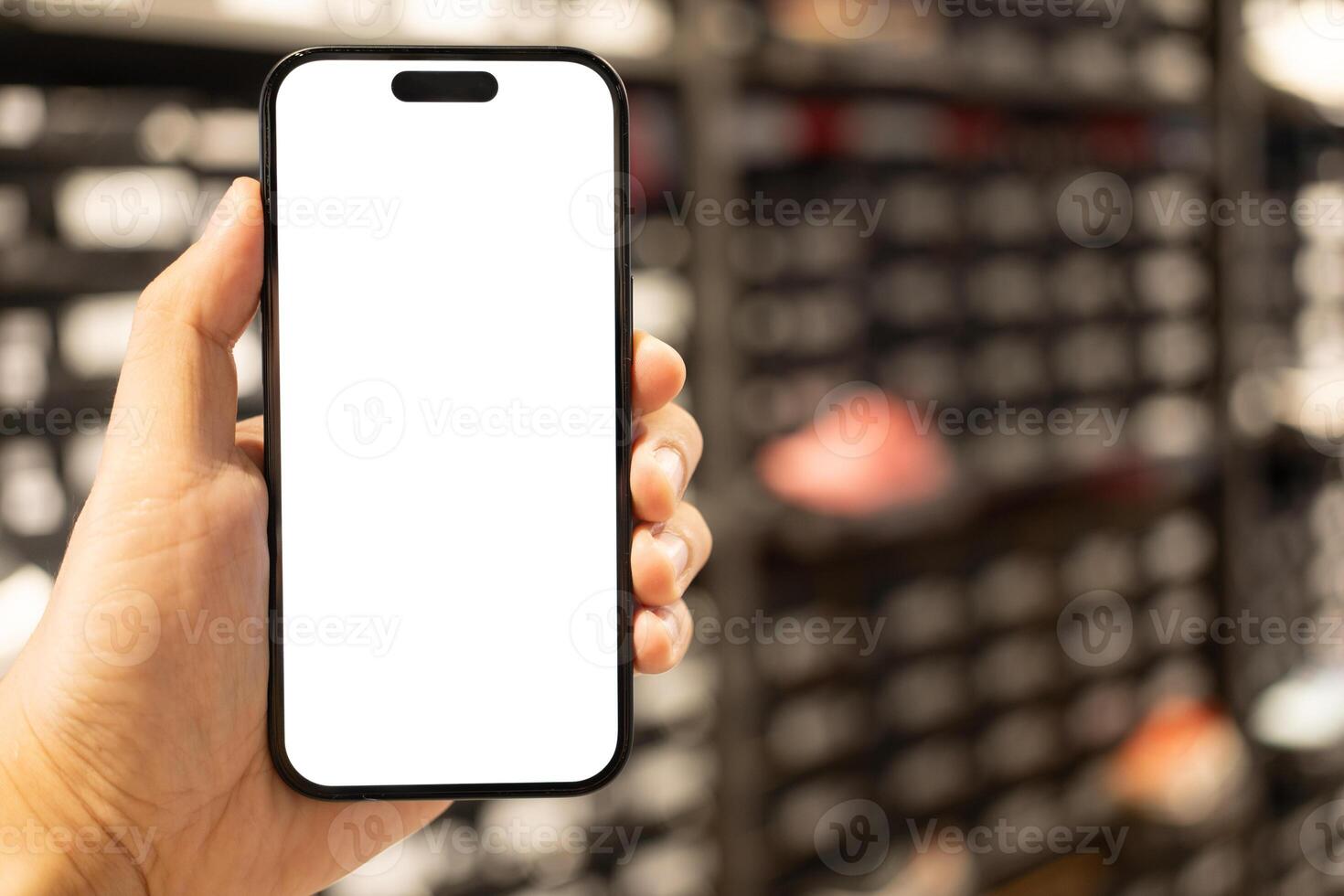 Hand Holding Blank Smartphone Screen in Retail Store. Mobile shopping, online commerce, in-store digital experiences, product information lookup, or advertising. photo