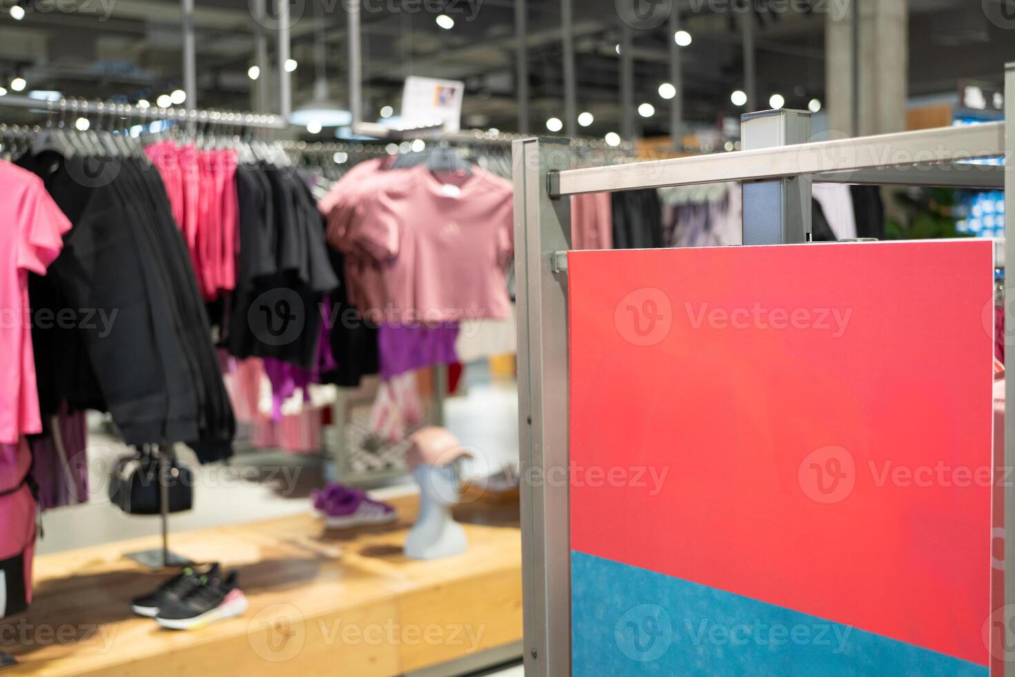 Blank Red Signboard in Fashion Retail Clothing Store. Empty red signboard inside a modern clothing retail store. Ideal for mockup, advertisement. photo