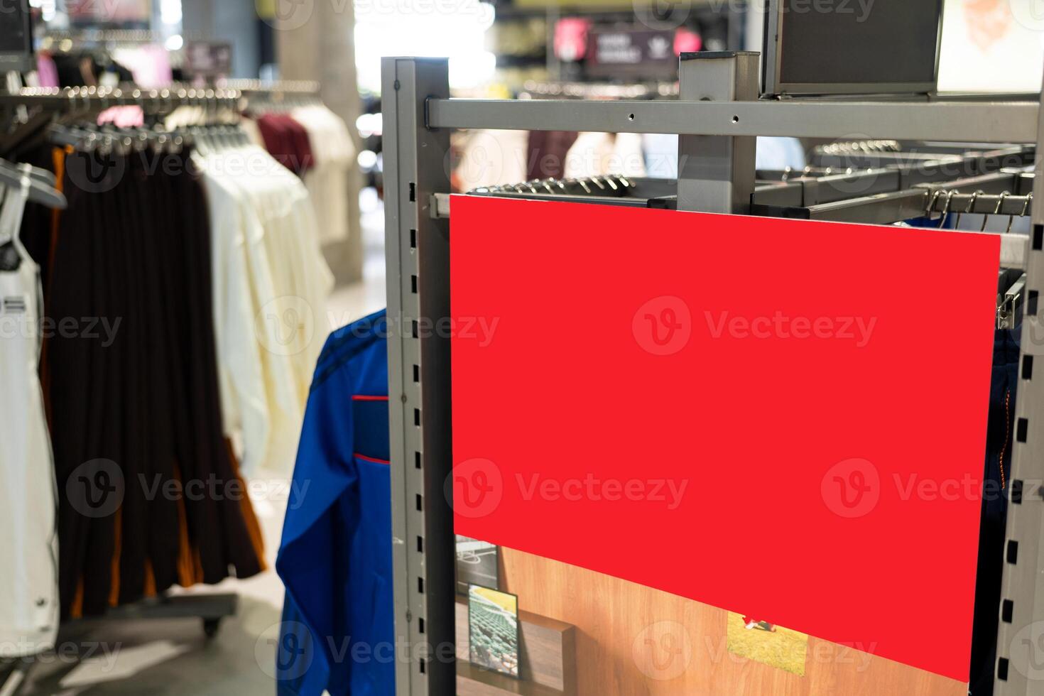 Blank Red Signboard in Fashion Retail Clothing Store. Empty red signboard inside a modern clothing retail store. Ideal for mockup, advertisement, or promotional. photo