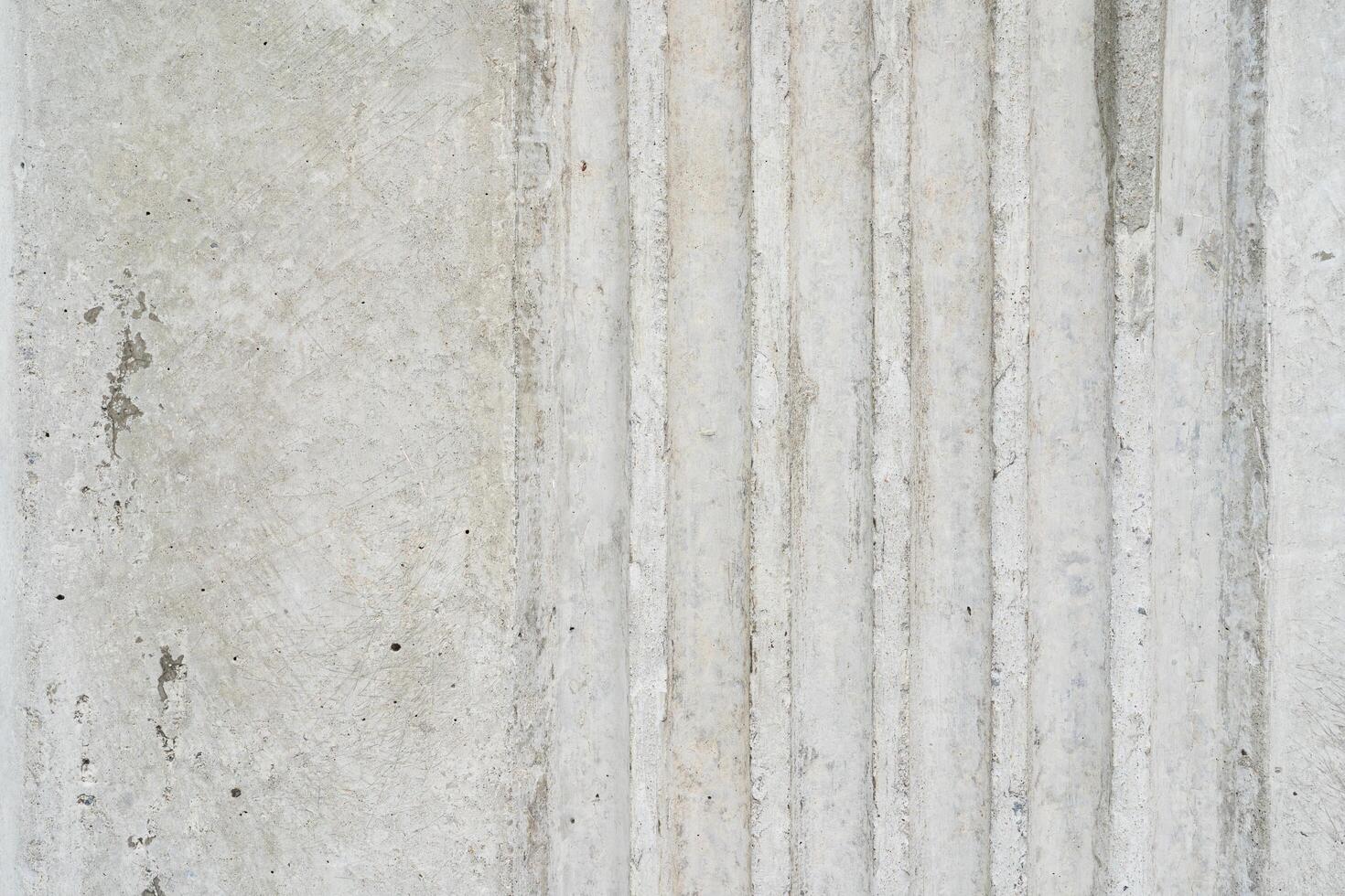 Textured Concrete Surface with Vertical Grooves. A detailed shot of a light grey concrete wall featuring a series of parallel vertical grooves. photo