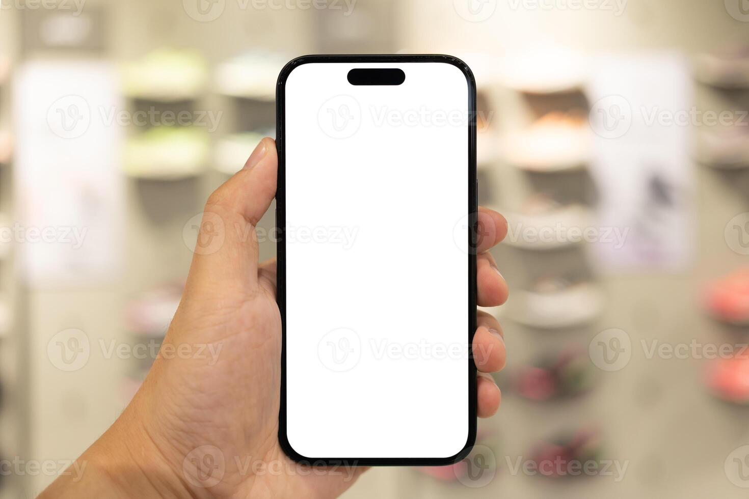 Hand Holding Blank Smartphone in Shoe Store. Mobile shopping for footwear, using retail apps, comparing prices online, or showcasing digital advertisements related to shoes. photo